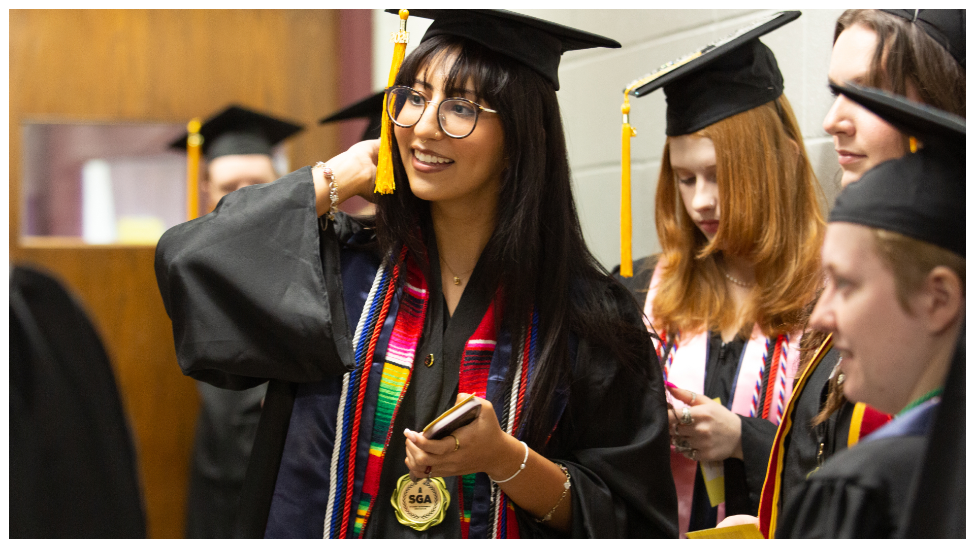 group of students getting ready to graduate, image is focusing on girl with glasses smiling